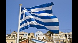 A Greek Flag Waving In Front Of A Village