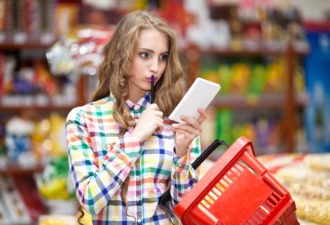 Beautiful Young Woman Looking At The Shopping List In A Supermarket
