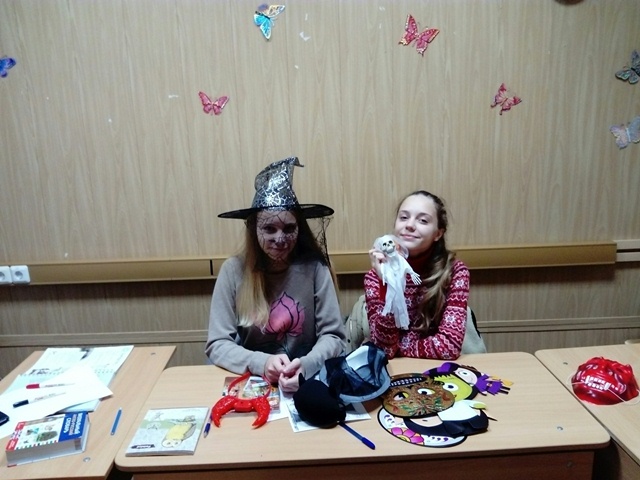 Two Girl Students With Halloween Puppets And Masks At School