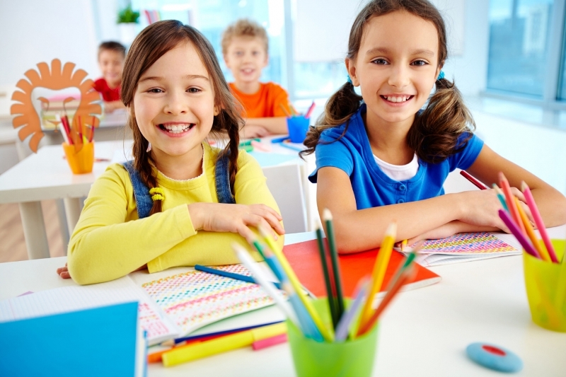 Two Girls Sitting At The Table At School And Smiling