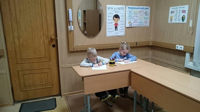 Two Little Pupils Writing On Their Notebooks